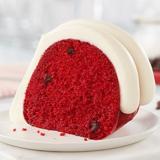Red Velvet slice showing topped with signature frosting and chocolate chips inside the cake slice
