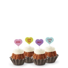 Mini Bundt cakes with white frosting, topped with conversation hearts in pink, lime, lavender, and light teal, displaying messages: XOXO, LOVE YOU, SWEET, and CUTIE PIE.