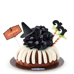 Last Chance! This bundt cake is decorated with frosting all around. It is topped with a black bow with a witch hat and legs sticking out of the cake. A card is attached and reads witch way to the cake?.