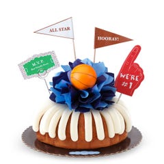 A Lemon bundt cake, decorated with a mini basketball on top of a bow with different shades of blue in the center of the cake.